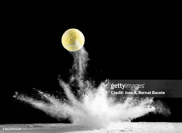 impact and rebound of a ball of tennis on a surface of land and powder on a black background - dribbling sport foto e immagini stock