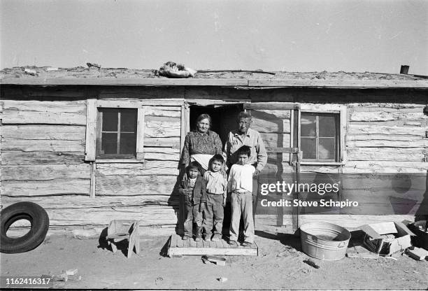 Portrait of an unidentified Oglala Sioux family as they stand on the stoop in front of their house on the Pine Ridge Indian Reservation, South...