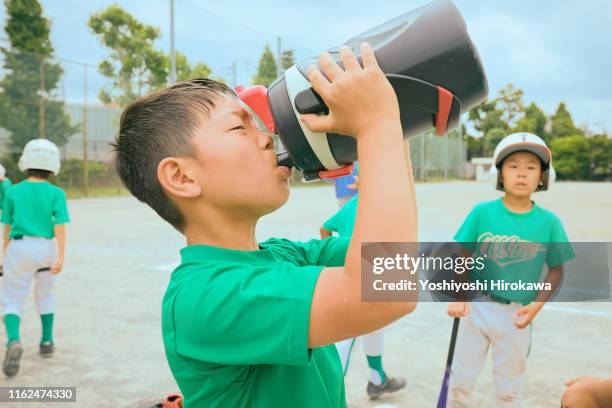 boy(6-7) baseball player drinking water from bottle - water canteen stock pictures, royalty-free photos & images
