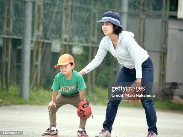 the boy protects the outfield with his mother in baseball practice - baseball mom stockfoto's en -beelden