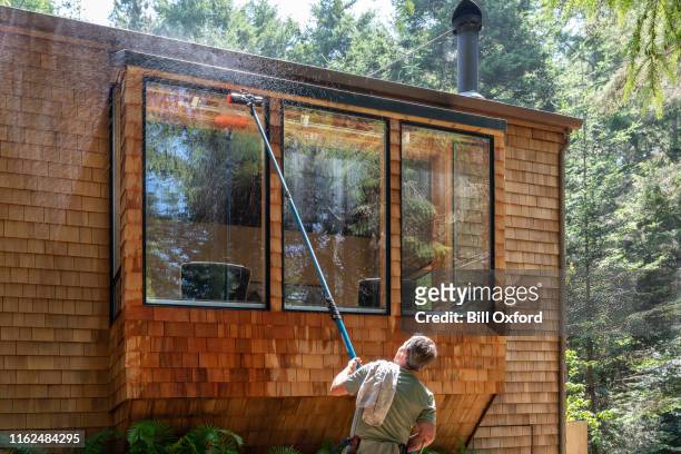 mann waschfenster mit langem stock und pinsel - window cleaner stock-fotos und bilder