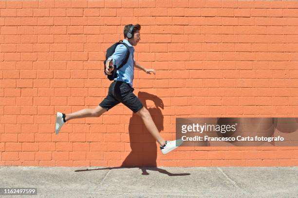 young student runs to school - european outdoor urban walls stockfoto's en -beelden
