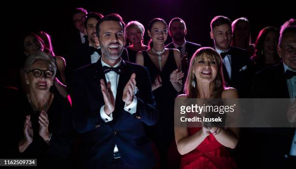feliz pareja aplaudiendo mientras ve ópera - ovación de pie fotografías e imágenes de stock