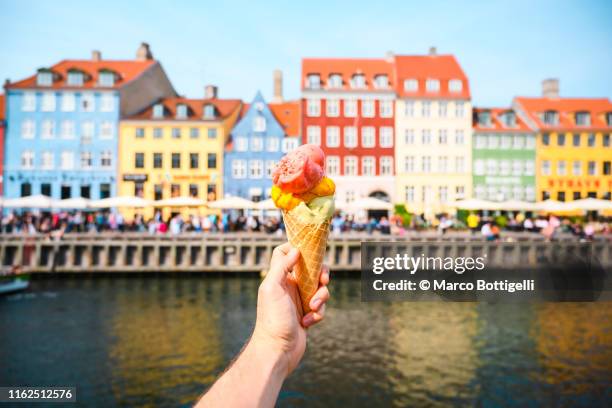 personal perspective of tourist holding an ice cream in front of nyhavn canal, copenhagen - house denmark stock-fotos und bilder