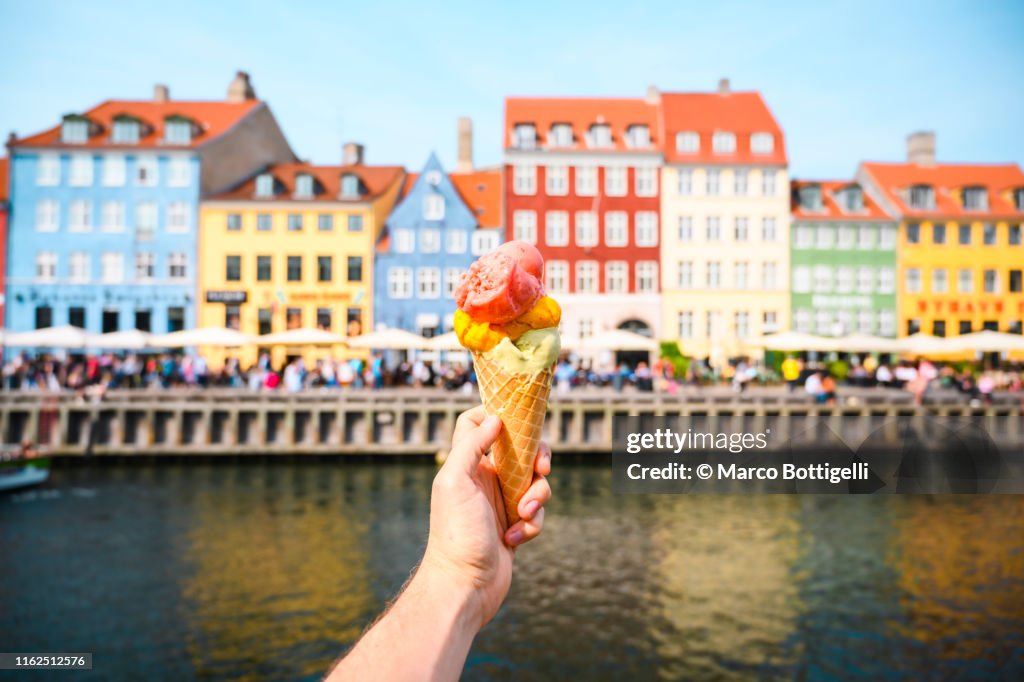 Personal perspective of tourist holding an ice cream in front of Nyhavn canal, Copenhagen