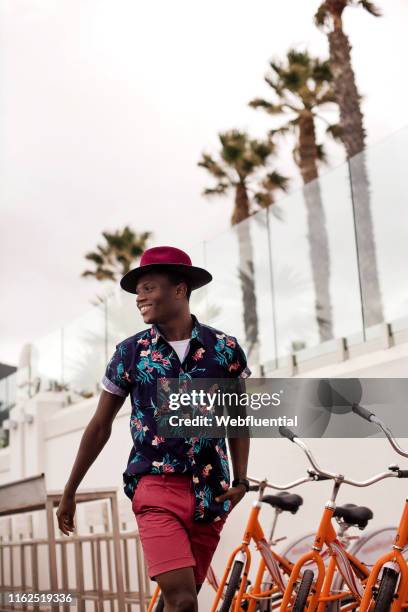 Young black South African man walking outdoors past bicycles