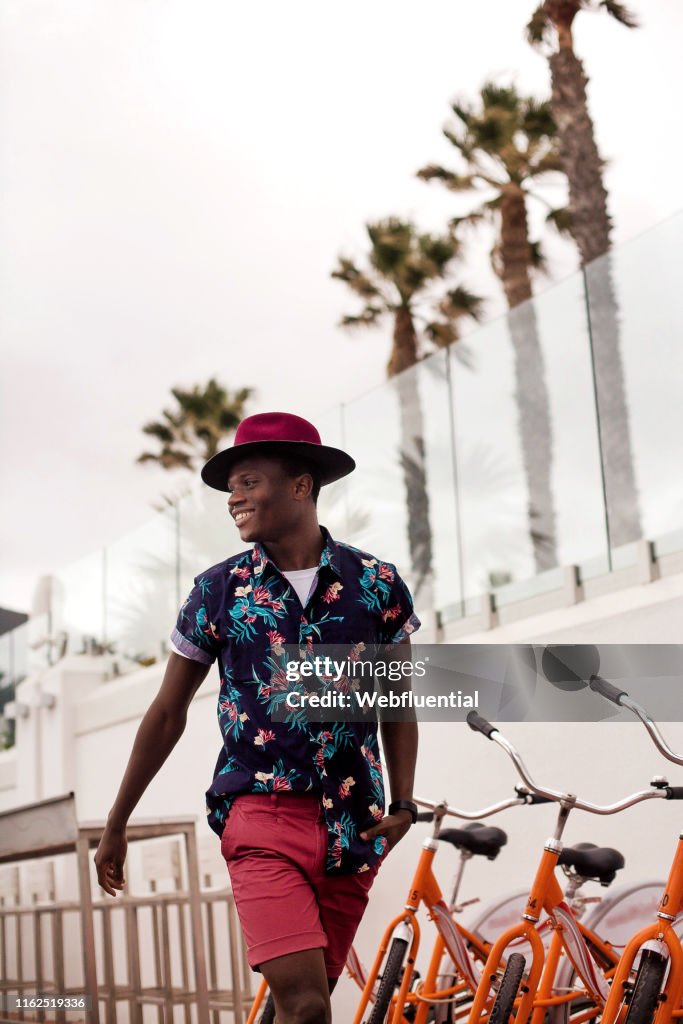 Young black South African man walking outdoors past bicycles