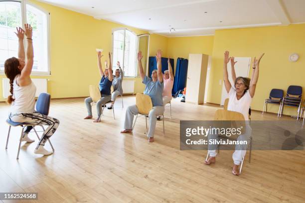 yoga class: senior women exercising on chair - chair stock pictures, royalty-free photos & images