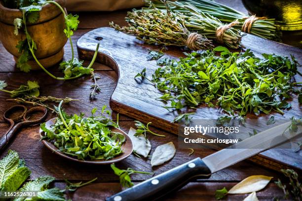 cutting board with chopped parsley on rustic wooden table - chopped herbs stock pictures, royalty-free photos & images