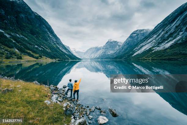 friends admiring the view on the banks of a norwegian fjord, norway - idyllic lake stock-fotos und bilder