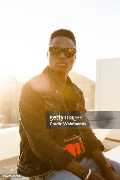 Young black man sitting on a roof top during sunset