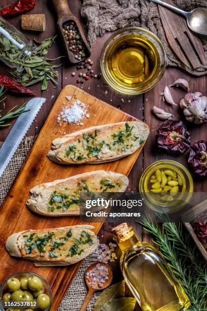 snack or appetizer of garlic basil and olive oil bruschetta on table in a rustic kitchen - garlic bread stock pictures, royalty-free photos & images