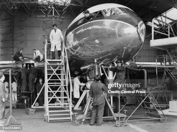 Engineers oversee the inspection of a British Overseas Airways Corporation de Havilland DH-106 Comet 1 passenger jet airliner in its hanger at...