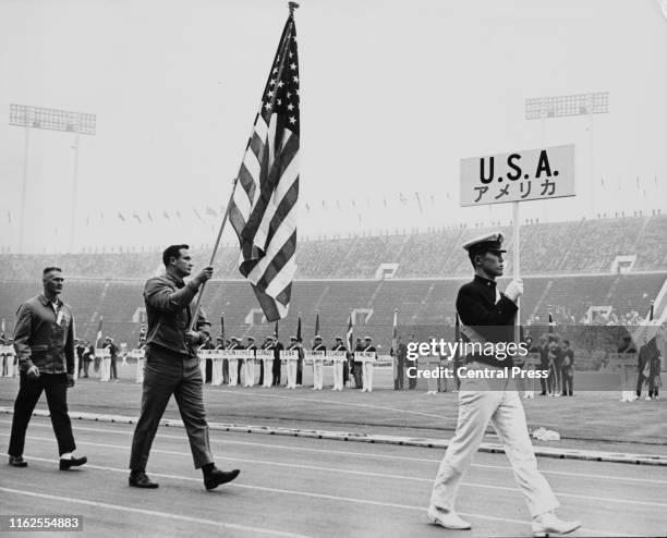 Double Olympic gold medalist in the shot put competition Parry O'Brien of the United States carries the stars and stripes national flag during the...