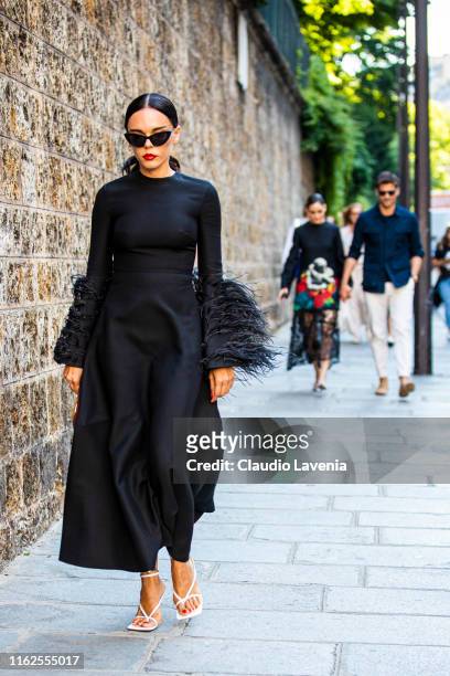 Evangelie Smyrniotaki, wearing a long black dress with feathers details, white heels and burgundy Valentino bag, is seen outside VALENTINO show...