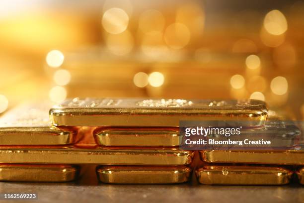 gold bullion bars stacked in a secure vault - gold bars stock-fotos und bilder