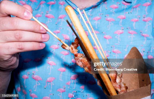 a close-up of a man wearing a brightly coloured shirt and holding food - flash stockfoto's en -beelden