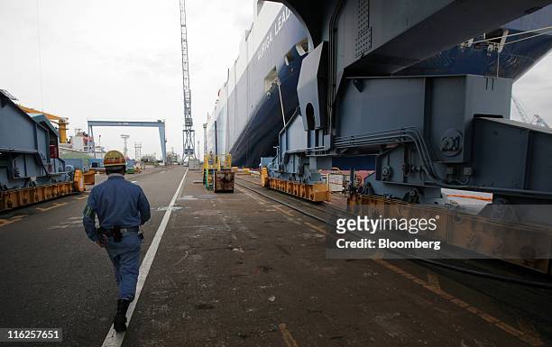 Worker walks near the Nippon Yusen K.K.'s car transporter ship, Auriga Leader, at Mitsubishi Heavy Industries Ltd.'s Honmoku plant in Yokohama city,...
