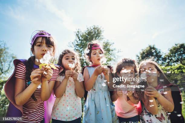 happy kids blowing dandelions - dandelion blowing stock pictures, royalty-free photos & images