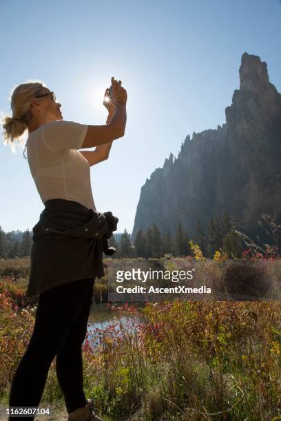 mujer toma fotografía con teléfono celular en follaje de otoño - smith rock state park fotografías e imágenes de stock