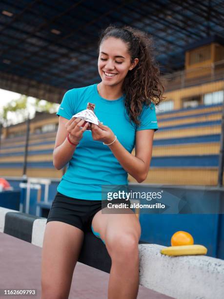 beautiful latin athlete eating a protein bar - sportsman imagens e fotografias de stock