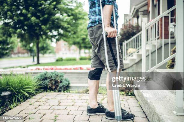 man using crutch after having knee sprain - knee crutch stock pictures, royalty-free photos & images