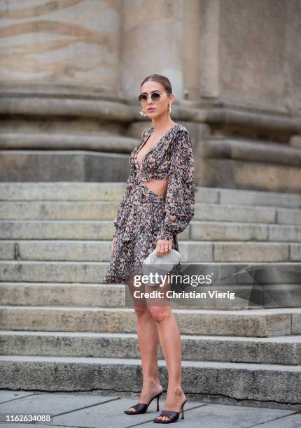 Ann-Kathrin Götze is seen wearing Zimermann dress with animal print, pouch and sandals Bottega Veneta, sunglasses Olivers People x The Row, earrings...