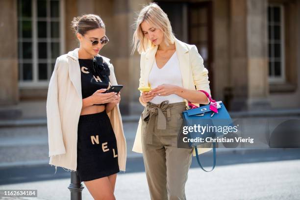 Ann-Kathrin Götze is seen showing her friend something on her smart phone wearing black cropped top with logo print and mini skirt Chanel, sunglasses...