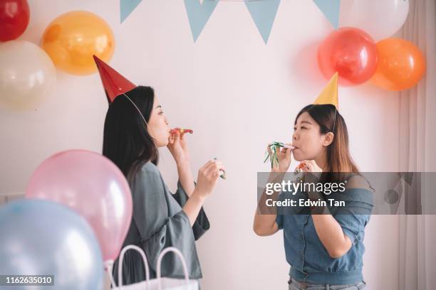 2 asian chinese female friends playing with party horn blower during the birthday party - party horn blower imagens e fotografias de stock