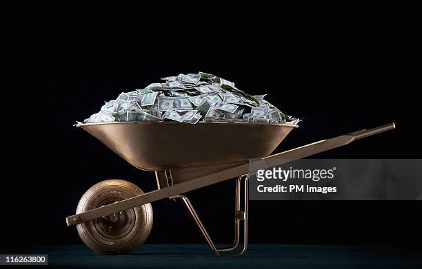 golden wheel barrel of money - wheelbarrow 個照片及圖片檔