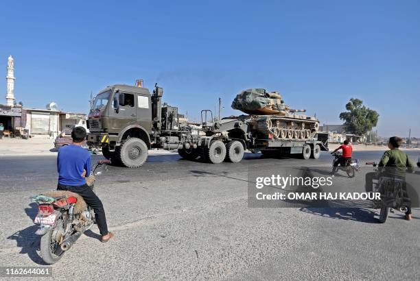 Inhabitants of Maaret al-Numan in Syria's northern province of Idlib watch a convoy of Turkish military vehicles reportedly heading toward the town...