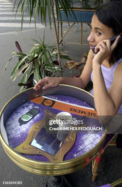 Une jeune femme est assise à une terrasse, le 17 août 2000 à Paris, autour d'une table pub. Fruit d'une start-up française, "Impact Diffusion", cette...