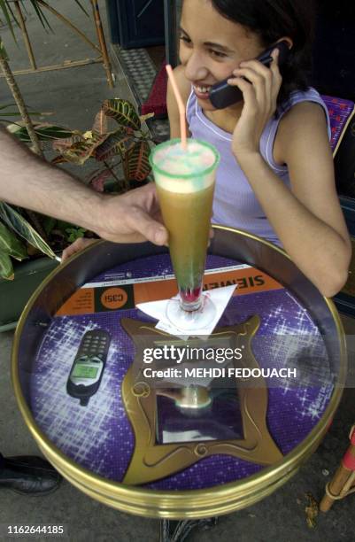 Une jeune femme est assise à une terrasse, le 17 août 2000 à Paris, autour d'une table pub. Fruit d'une start-up française, "Impact Diffusion", cette...