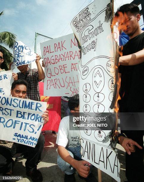 Angry subscribers burn a cardboard cut-out of a mobile telephone outside the office of the goverment's National Telecommunications Commission , 24...