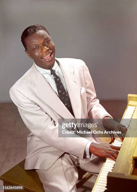 Singer and pianist Nat "King" Cole poses for a portrait sitting at the piano in an image that was created using the Carbro TRI-COLOR CARBRO camera...