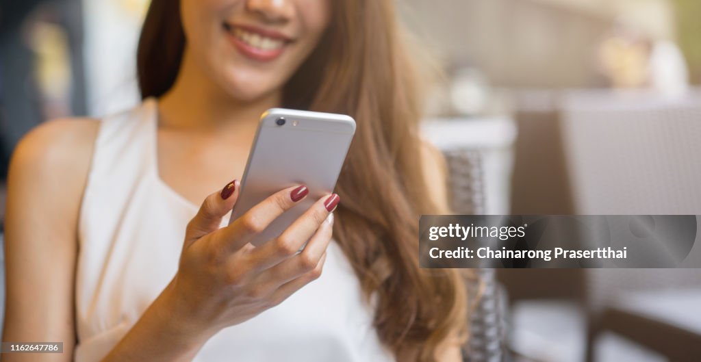 Nahaufnahme junge schöne asiatische Frau suchen auf Smartphone für Video-Online-Chat mit Freunden oder surfen Sie im Internet oder spielen mobile Anwendung in Relax-Zeit, Millennial-Technologie-Lifestyle-Konzept