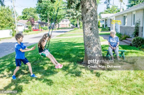 boy pushing sister on swing - boy pushing girl in swing stock pictures, royalty-free photos & images