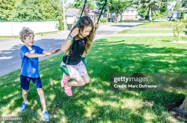 boy pushing sister on swing - boy pushing girl in swing stock pictures, royalty-free photos & images