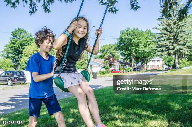 boy pushing sister on swing - boy pushing girl in swing stock pictures, royalty-free photos & images