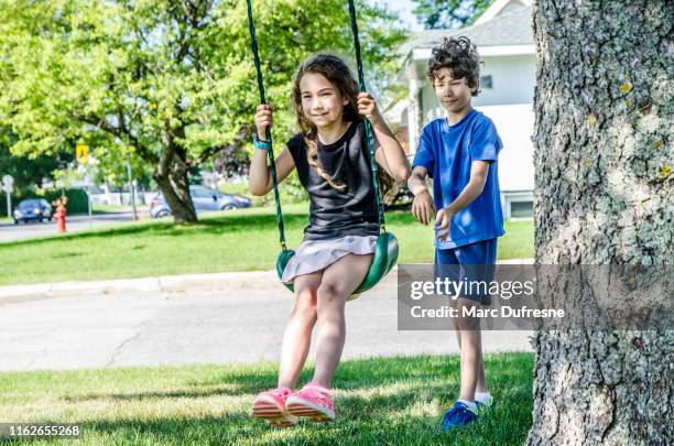 boy pushing sister on swing - boy pushing girl in swing stock pictures, royalty-free photos & images