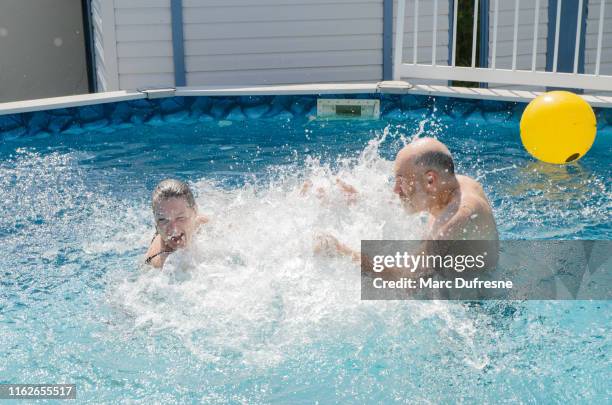 heterosexual couple splashing in swimming pool - famille couple stock pictures, royalty-free photos & images