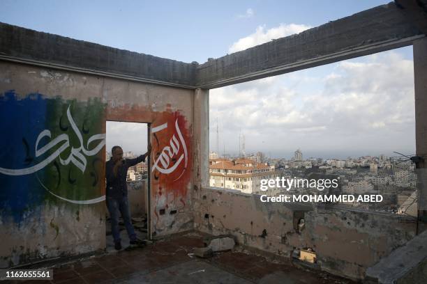 Palestinian man gazes at Gaza City from a rooftop ornated with Arabic calligraphy on August 19, 2019.