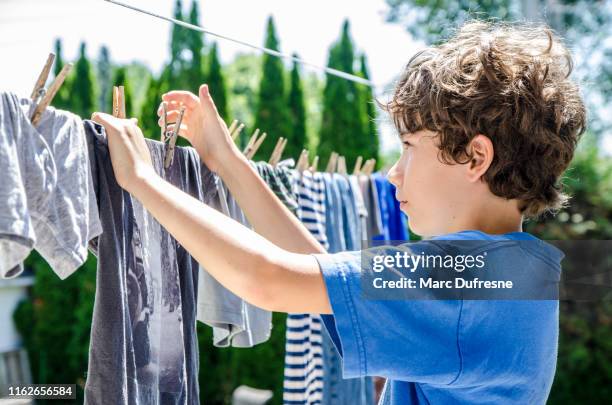 pequeño niño colgando ropa en tendedero - ropa tendida fotografías e imágenes de stock