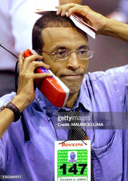 Ricardo Lemos, a stock broker of the Sao Paulo Stock Market Value , listens on the phone to the orders to buy and sell during a stock market session,...