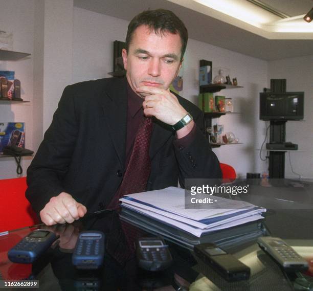 Photo récente de Denis Martin, Directeur général de l'usine "Philips" du Mans, posant à son bureau derrière quelques modèles de téléphones portables...