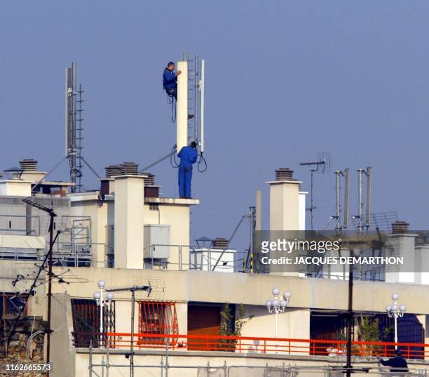 Des techniciens installent des relais téléphoniques sur le toit d'un immeuble parisien, le 20 mars 2003. La ville de Paris a signé le même jour une...