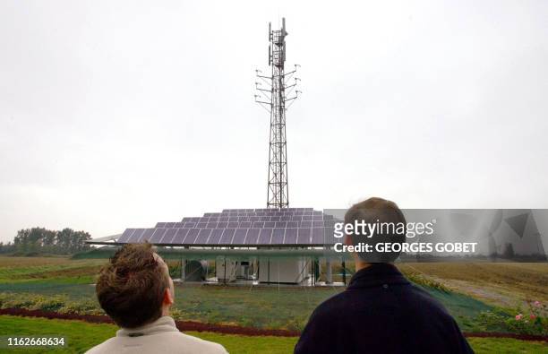Deux personnes regardent le nouveau site de téléphonie mobile, unique en Europe, alimenté en énergie solaire et éolienne, le 05 octobre 2005 à...
