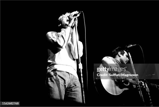 Art Garfunkle, clasping the mike with both hands, and Paul Simon looking down and singing, performing on stage at the Monterey International Pop...