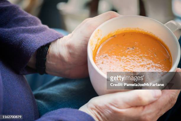 pov, senior woman holding cup of tomato soup on lap - soup stock pictures, royalty-free photos & images
