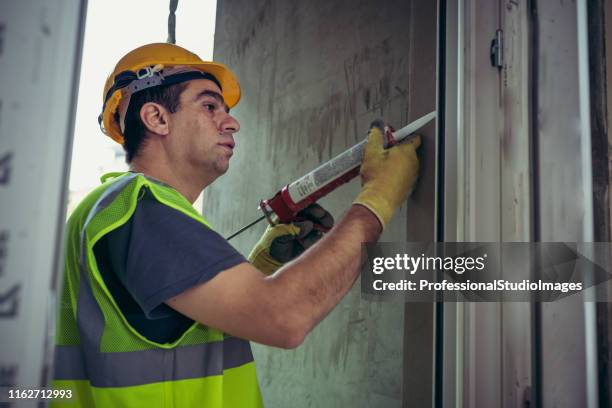 bouwvakker met siliconen lijm - caulking stockfoto's en -beelden